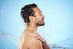 Man, water splash and clean for skincare, wellness and health with beauty, grooming and on blue studio background. Cleaning, male and shower for washing, organic care and hygiene for natural skin.
