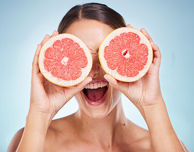 Buy stock photo Face, beauty skincare and woman with grapefruit in studio isolated on a blue background. Organic cosmetics, healthy diet and happy female model holding fruit for vitamin c, facial care and wellness.