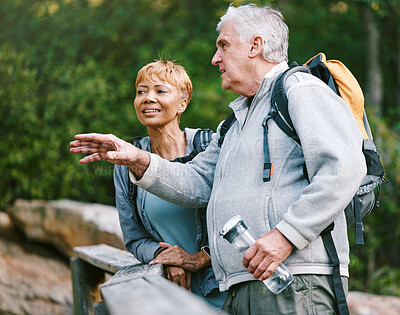 Buy stock photo Couple, elderly and hiking in forest with fitness and interracial, talking about view and relax while trekking. Retirement, exercise and hike in nature with water bottle for hydration and travel.