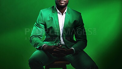 Buy stock photo Fashion, suit and black man model with a formal outfit sitting on a chair while posing in a studio. Elegant, trendy and African male in luxury, stylish and fancy clothes isolated by green background.