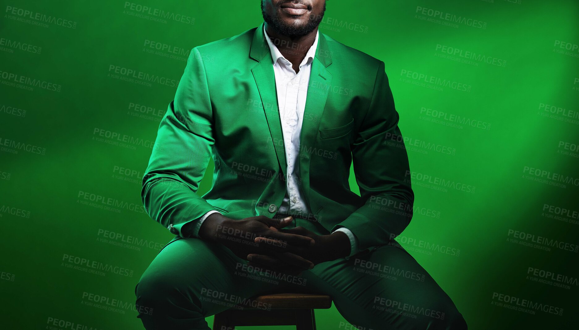 Buy stock photo Fashion, suit and black man model with a formal outfit sitting on a chair while posing in a studio. Elegant, trendy and African male in luxury, stylish and fancy clothes isolated by green background.