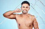 Face, water splash and man with toothbrush for cleaning in studio on blue background. Dental veneers, hygiene and portrait of happy male model brushing teeth for oral wellness, health or fresh breath