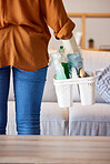 Woman, cleaning services and basket with product tools in living room, lounge and home. Closeup cleaner, maid and container of chemical detergent for housekeeping, maintenance and disinfection safety