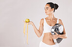 Fitness, health and woman with scale and apple for weightloss, diet and nutrition on white background studio. Exercise, wellness and girl with fruit, balance and measuring tape for healthy lifestyle