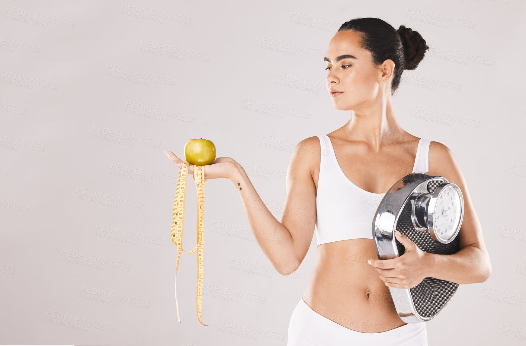 Buy stock photo Fitness, health and woman with scale and apple for weightloss, diet and nutrition on white studio background. Exercise, wellness and girl with fruit, balance and measuring tape for healthy lifestyle