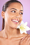 Beauty, wellness and woman with a lily flower in studio for a health, cosmetic and natural face routine. Skincare, health and healthy girl model from Brazil with floral isolated by purple background.