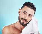 Man face, towel and skincare while wet after a shower, facial or bath for skincare, hygiene and dermatology on blue. Portrait of happy male model in studio for clean body for health and wellness