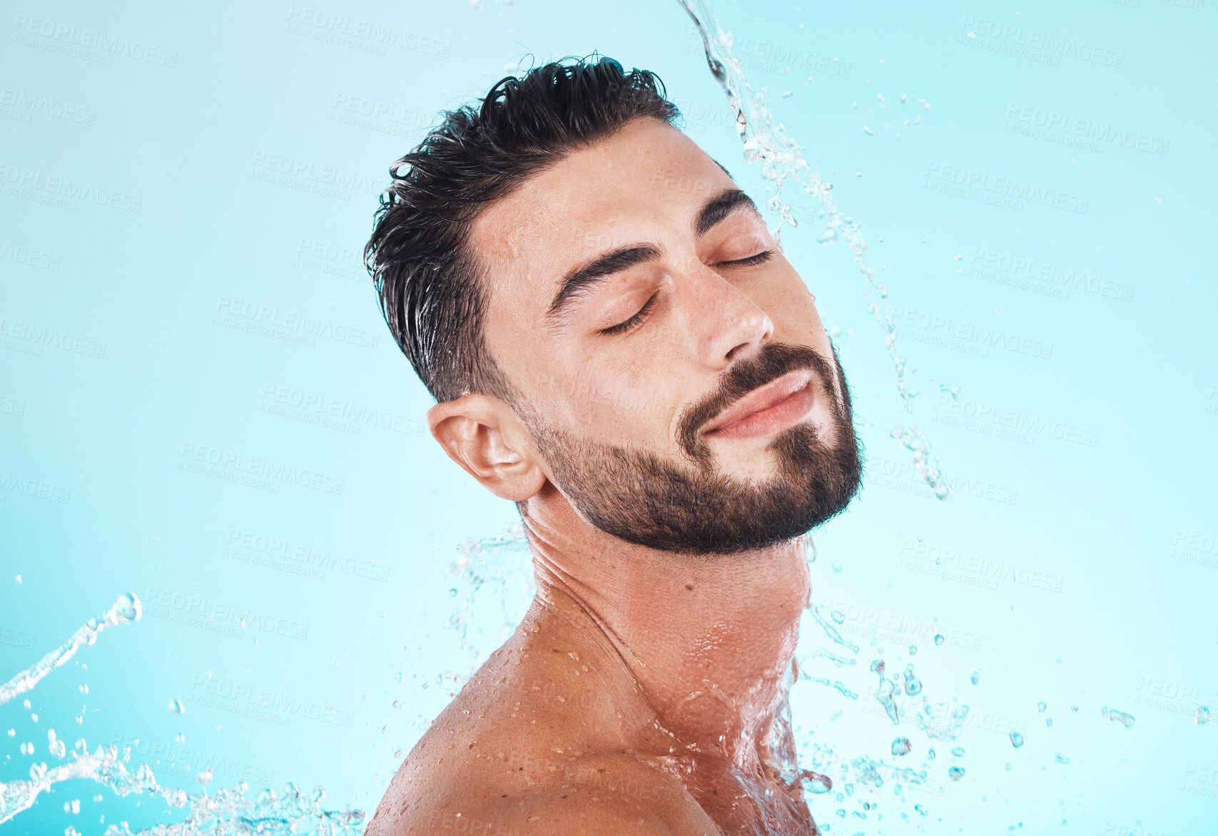 Buy stock photo Water, splash and skincare with face of man for shower, self care and natural cosmetics. Luxury, hydration and refreshing with model for dermatology, wellness and cleaning on blue background studio