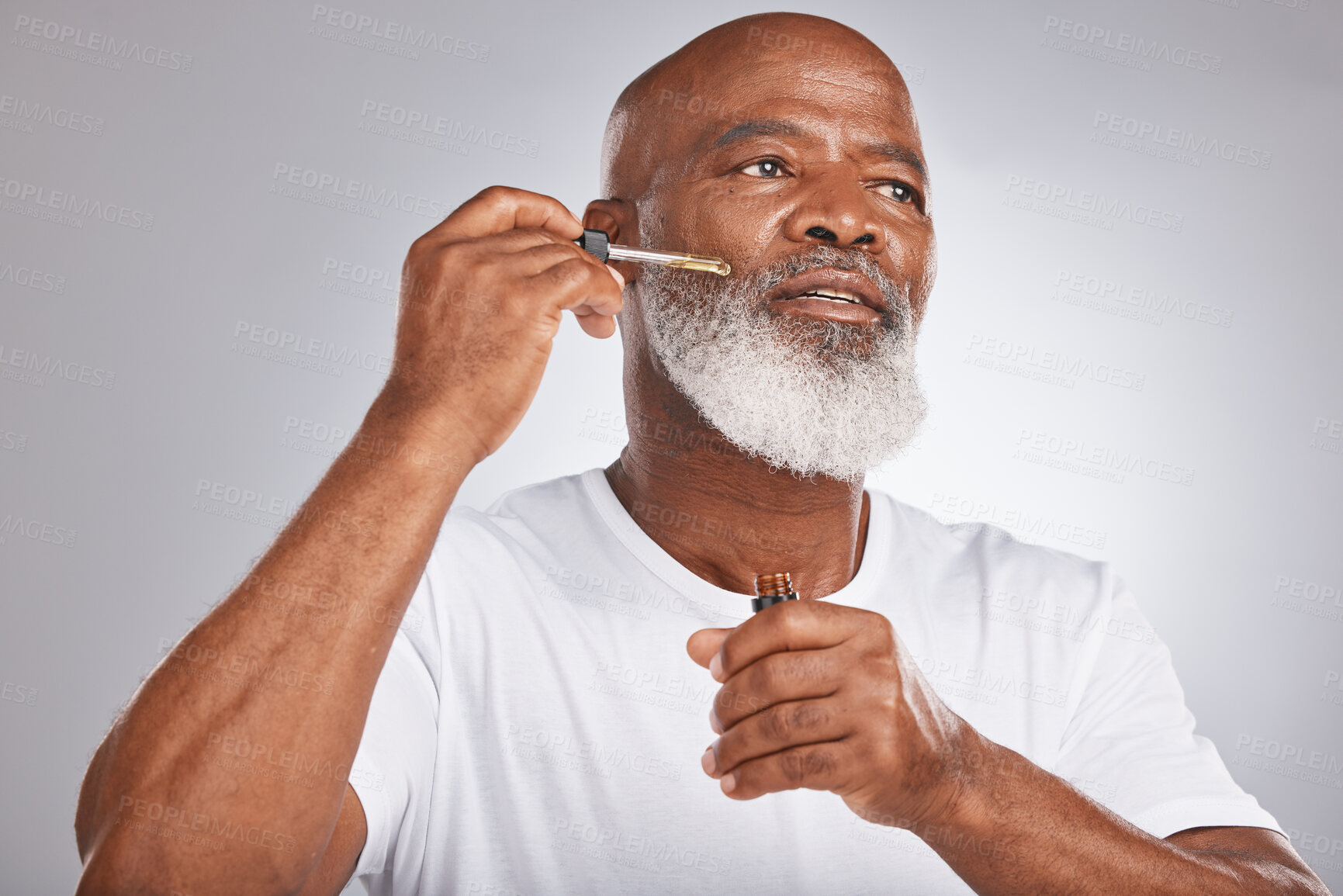 Buy stock photo Skincare, wellness and man with a face serum in a studio for a healthy, cosmetic and natural routine. Beauty, cosmetics and African male with a facial oil treatment isolated by a gray background.