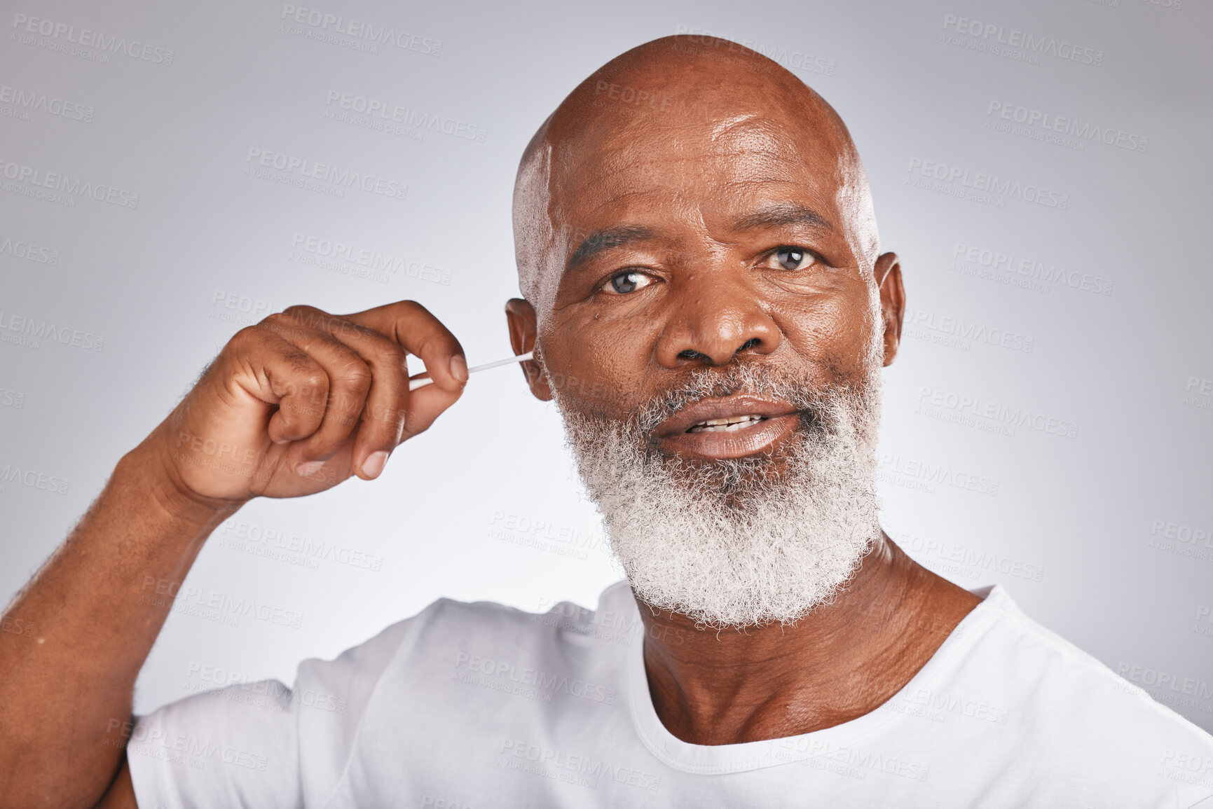 Buy stock photo Senior black man, ears cleaning and cotton bud for wax removal, grooming hygiene and self care cosmetics earwax cleaner in white studio background. Elderly african model, face and body care cleansing