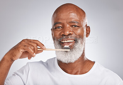Buy stock photo Portrait, black man and brushing teeth with toothbrush for dental wellness, healthy lifestyle or cleaning cosmetics in Nigeria. Happy male model, oral mouth care and mature smile on studio background
