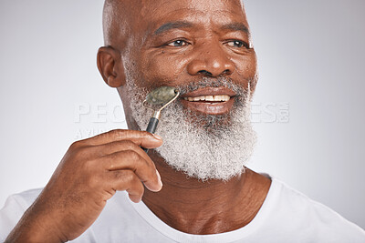 Buy stock photo Black man, facial roller and skincare to massage skin for self care with dermatology beauty tool. Headshot of a happy senior male with a stone on grey studio background for spa treatment for the face