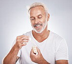 Skincare, health and senior man with face serum in a studio for a wellness, cosmetic and natural face routine. Cosmetics, beauty and elderly guy with facial oil for skin treatment by gray background.
