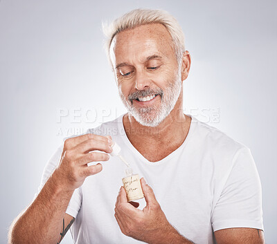 Buy stock photo Skincare, health and senior man with face serum in a studio for a wellness, cosmetic and natural face routine. Cosmetics, beauty and elderly guy with facial oil for skin treatment by gray background.