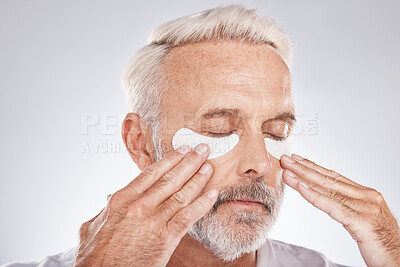 Buy stock photo Eyes patch, senior man and skincare face in studio for self care dermatology, facial and cosmetics advertising in morning. Model with hands application of collagen mask or anti aging beauty product
