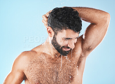 Buy stock photo Water, shower and a man washing hair with shampoo in studio on a blue background for beauty or hygiene. Hair, cleaning or treatment with a handsome male wet in the bathroom while bathing for haircare