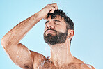 Water, shower and a man washing hair with shampoo in studio on a blue background for beauty or hygiene. Hair, cleaning and bathroom with a handsome male wet in the bathroom while bathing for haircare
