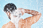 Shower, water and man with soap for cleaning, washing and hygiene on blue background in studio. Grooming, bathroom and back of male with foam, sponge and water splash for skincare, wellness and spa