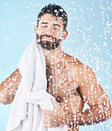 Clean, man with towel and beauty, body hygiene with bokeh overlay and grooming against blue background. Skincare with shower and smile, clean cosmetic care and cotton fabric, facial and wellness