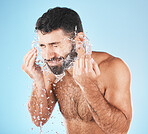 Man, water splash face and cleaning in studio for wellness, health and self care groom by blue background. Model, bathroom and water with hands for healthy facial, self love and cosmetics by backdrop