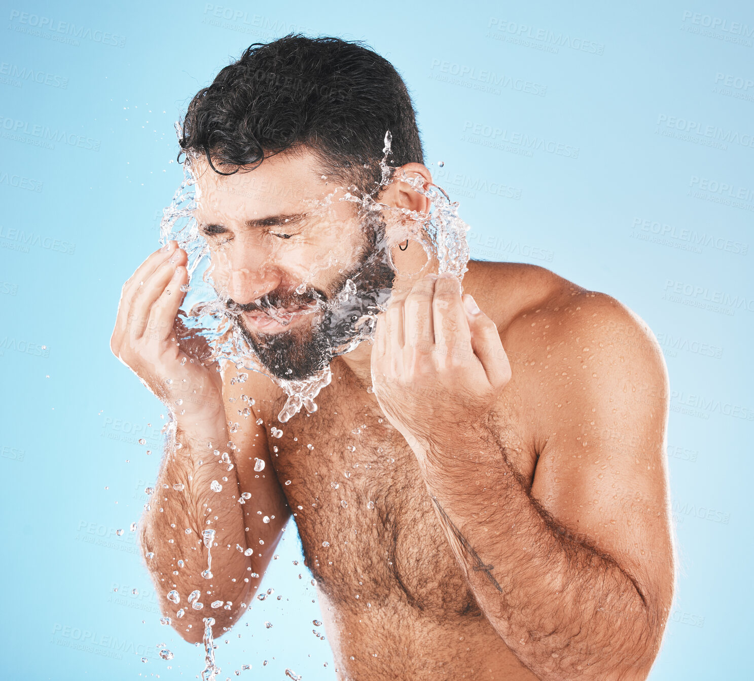 Buy stock photo Man, water splash face and cleaning in studio for wellness, health and self care groom by blue background. Model, bathroom and water with hands for healthy facial, self love and cosmetics by backdrop