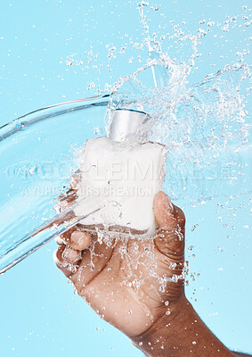 Buy stock photo Water splash, black man and hand with skincare bottle in studio on a blue background. Hygiene, cleaning and male model holding lotion cosmetics or moisturizer product for beauty or skin health.