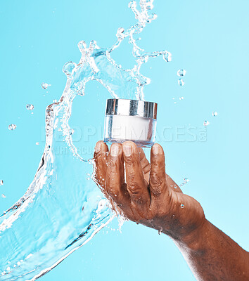 Buy stock photo Hand, water splash and black man with cream for skincare in studio on a blue background. Cosmetics, hygiene and male model holding lotion, creme or moisturizer product for healthy skin and beauty.