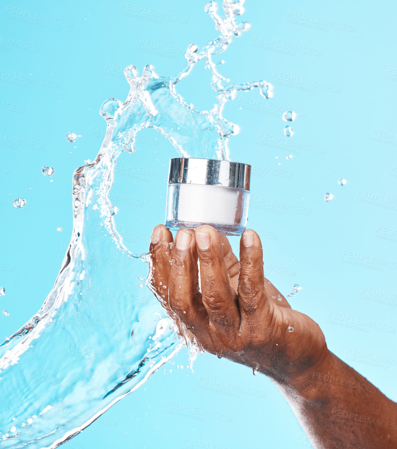 Buy stock photo Hand, water splash and black man with cream for skincare in studio on a blue background. Cosmetics, hygiene and male model holding lotion, creme or moisturizer product for healthy skin and beauty.