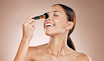 Makeup, brush on face and woman with beauty cosmetics mockup and wellness against studio background. Facial, treatment and cosmetic equipment, smile and foundation application with tools and skincare