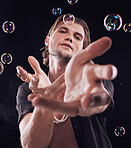 Bubbles, hands and man in studio for magic portrait, art performance and creative by black background. Alluring model, soap and rainbow light with dark mystery aesthetic or sexy show by backdrop