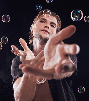 Buy stock photo Bubbles, hands and man in studio for magic portrait, art performance and creative by black background. Alluring model, soap and rainbow light with dark mystery aesthetic or sexy show by backdrop