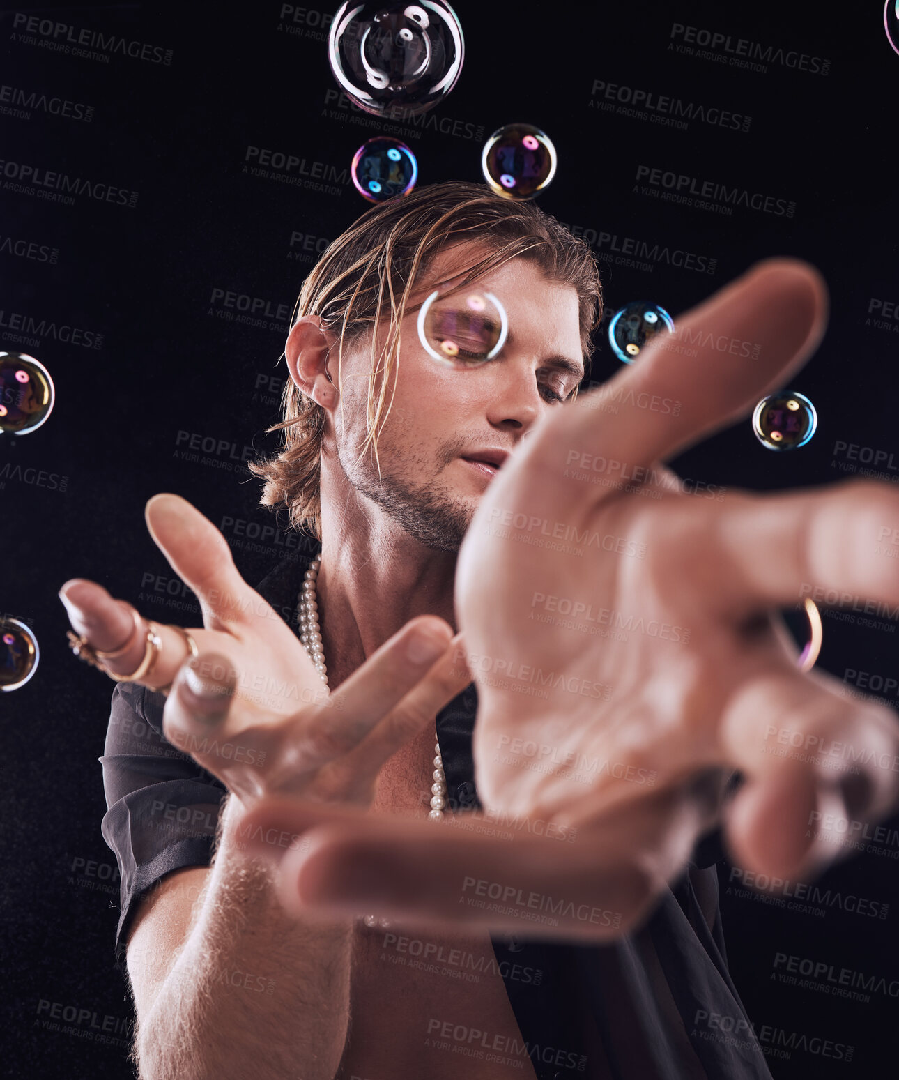 Buy stock photo Man, hands and bubbles in studio for magic, art performance or creative show by black background. Model, artist and soap with rainbow light, dark mystery aesthetic or theater presentation by backdrop