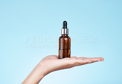 Buy stock photo Hand, product and serum with a woman in studio on a blue background to promote an antiaging treatment. Skincare, beauty and bottle with a female model holding a container for cosmetic advertising