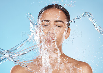 Buy stock photo Skincare, woman and water splash for shower, face cleaning and beauty against blue studio background. Latino female, girl and wet for cosmetics, face and hydration for dermatology and natural care
