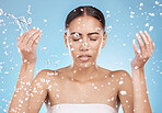 Woman skincare, washing face or water splash on blue background studio for dermatology wellness, healthcare hygiene maintenance or grooming. Beauty model, hands or wet water drops for facial cleaning