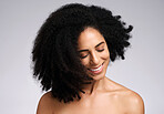 Happy, natural and hair care shake of black woman satisfied with cosmetic treatment texture and volume. Self love, smile and happiness of african hair and skincare girl in gray studio background.