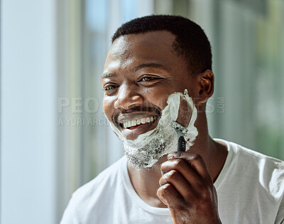 Buy stock photo Face, shaving and razor with a black man grooming in the bathroom mirror of his home for beauty or skincare. Beard, shave and blade with a handsome male in the morning for his hair removal routine