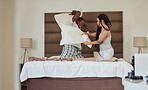 Love, pillow fighting and play with a black couple having fun in the bedroom of their home tofether in the morning. Dating, playful and joking with a man and woman playing or bonding on the bed