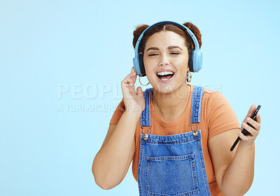 Buy stock photo Headphones, woman student and phone music streaming of a gen z model with blue studio background. Isolated, happy and freedom of a person listening to web radio and podcast audio with a smile