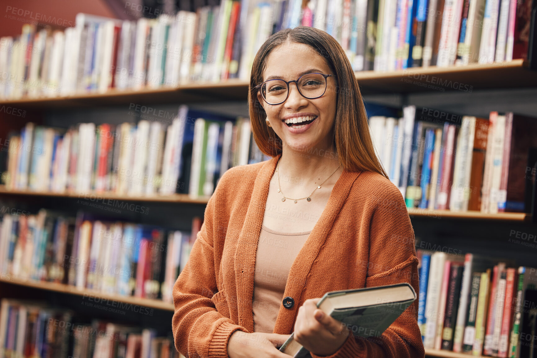 Buy stock photo Face, student and woman in university in library ready for learning. Portrait, education and happy female from Brazil standing by bookshelf with book for studying, knowledge and literature research.