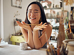 Portrait, pottery and art with an asian woman in her studio or workshop for design and creative hobby. Happy, smile or designer with a female artist working in her small business startup for ceramics