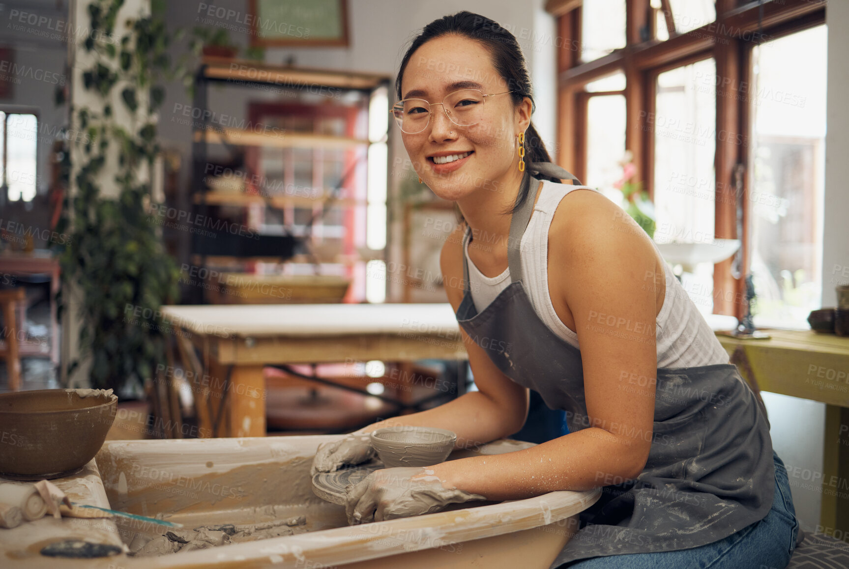 Buy stock photo Pottery, startup business and creative woman portrait in her workshop for art with hands in mud. Asian artist with potter wheel for clay or ceramic retail industry, trade or production with pride