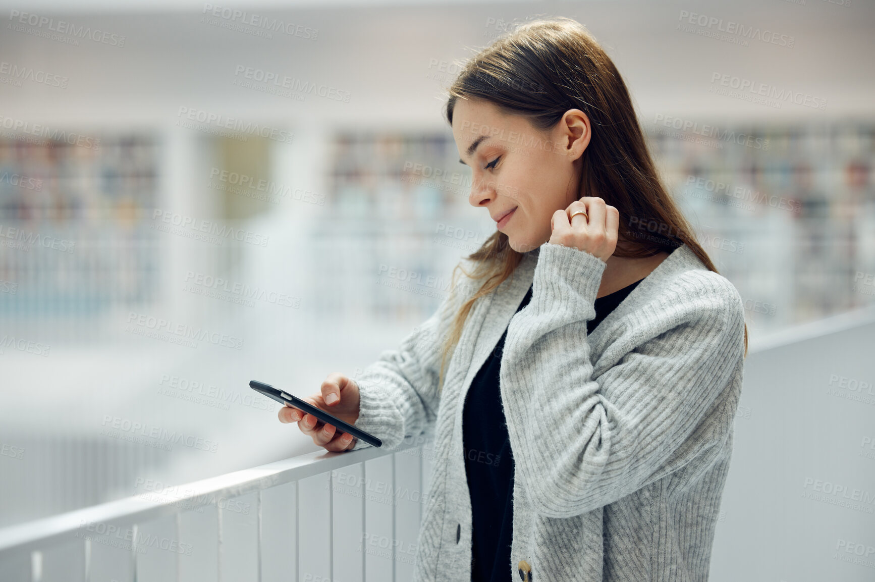 Buy stock photo Woman, phone and smile for social media, networking or chatting in communication at a library. Happy female smiling for texting, research or browsing for books on smartphone at big book store or mall