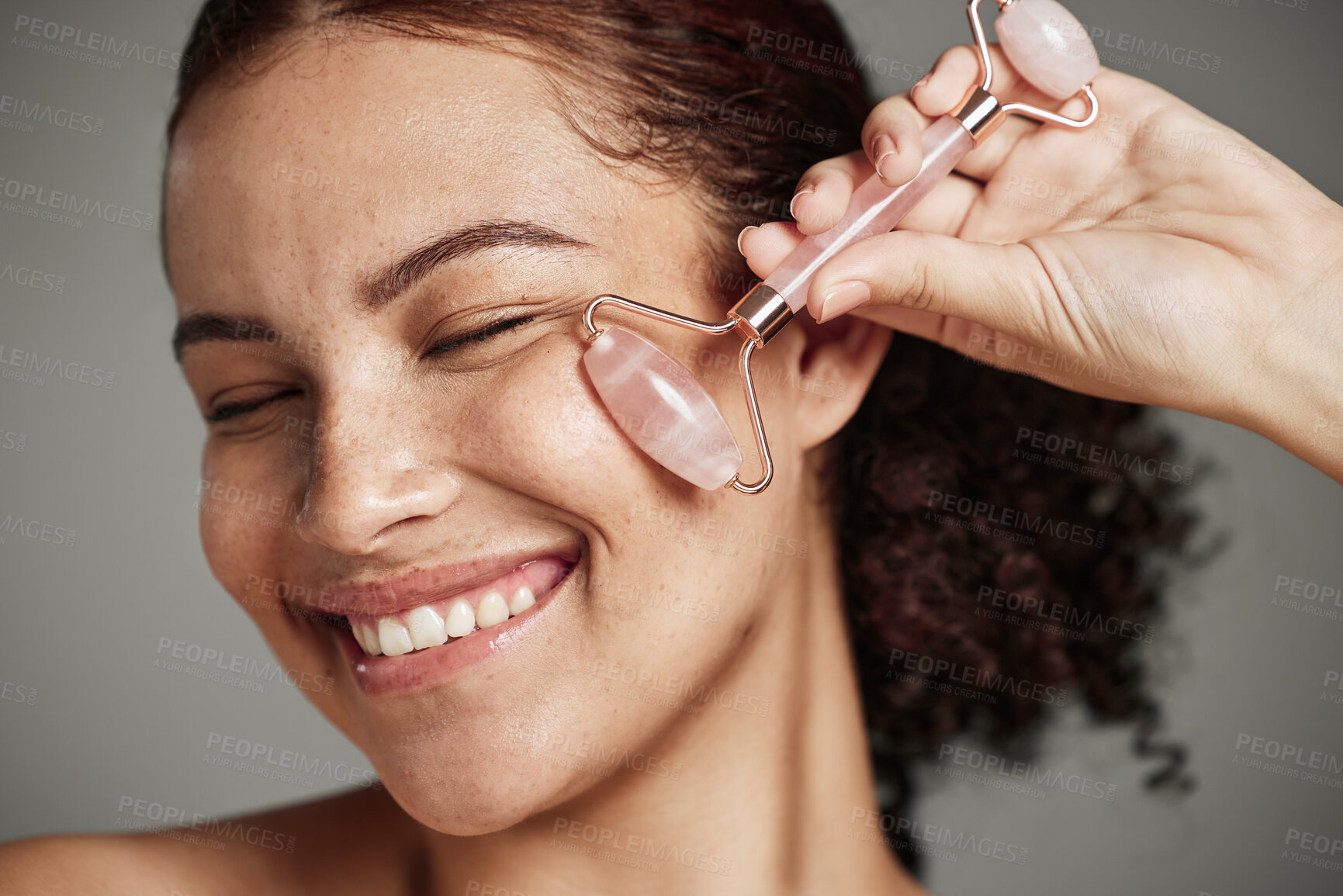 Buy stock photo Woman, face and smile with roller for skincare cosmetics, beauty or self love and care against grey studio background. Closeup of female smiling with rolling tool in satisfaction for makeup treatment