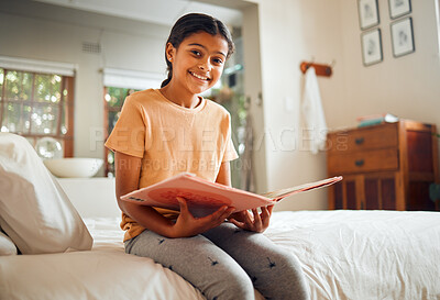 Buy stock photo Happy little girl, reading book and bed with smile for story time, education or learning in comfort at home. Portrait of cute female child smiling in happiness holding textbook to read in the bedroom