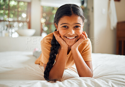 Buy stock photo Portrait, children and bedroom with an indian girl lying on her bed at home over the weekend to relax. Kids, face and smile with a happy female child resting or relaxing alone in her house