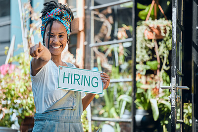 Buy stock photo Small business, manager or black woman with a hiring sign at door entrance in floral retail store. Advertising, marketing and happy entrepreneur smiles pointing with job offer message at flower shop