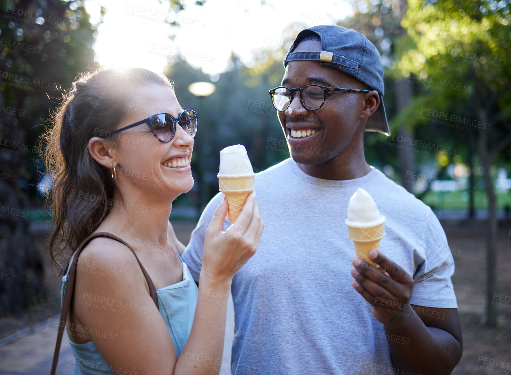 Buy stock photo Interracial couple, laughing and ice cream in a park for funny joke, conversation or bonding together. Happy man and woman sharing laugh with smile for humor, trip or holiday with desert in nature