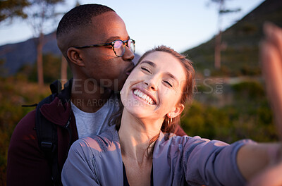 Buy stock photo Interracial couple, kiss and smile for selfie, travel or love for adventure, journey or hiking together in nature. Happy man kissing woman smiling in happiness for photo moments, trip or traveling