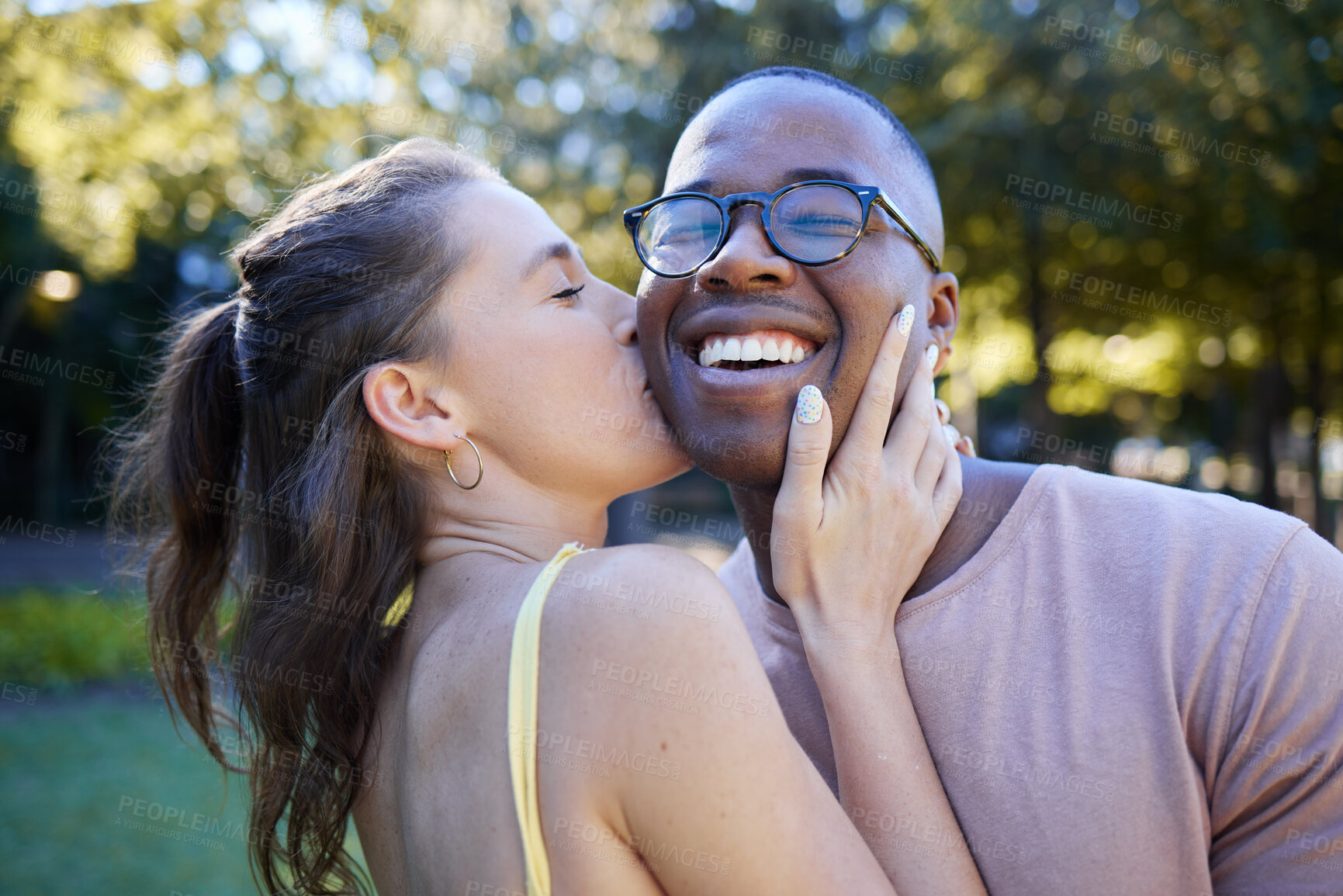 Buy stock photo Woman kiss man, happiness and date in park, outdoor in nature with love and commitment in interracial relationship. Trust, support and happy couple, content with smile on face and fresh air